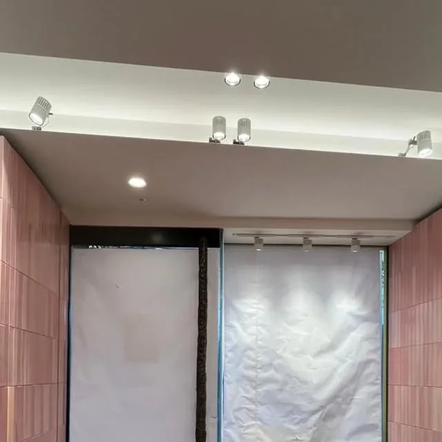 Interno contemporaneo con controsoffitto illuminato e rivestimenti rosa